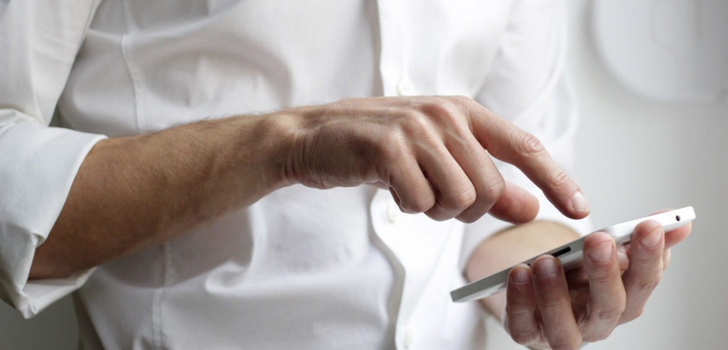man in white shirt on phone looking at click to messenger ads