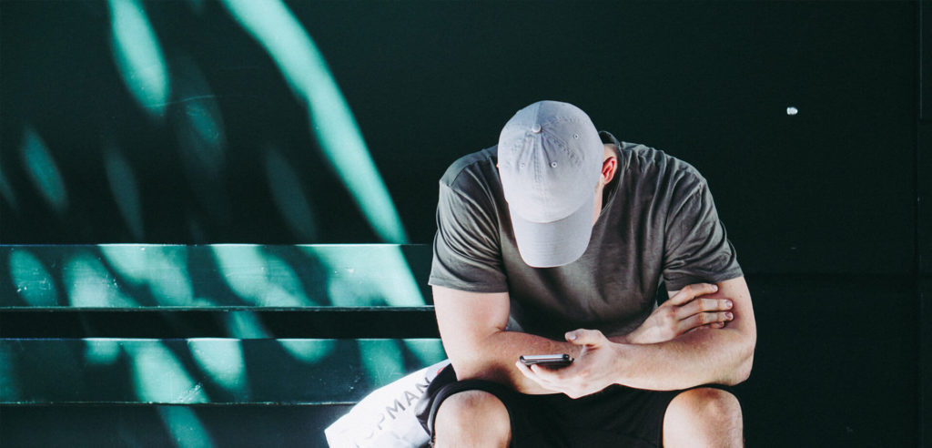 man on green bench on cell phone looking at how companies fail to convert their customers