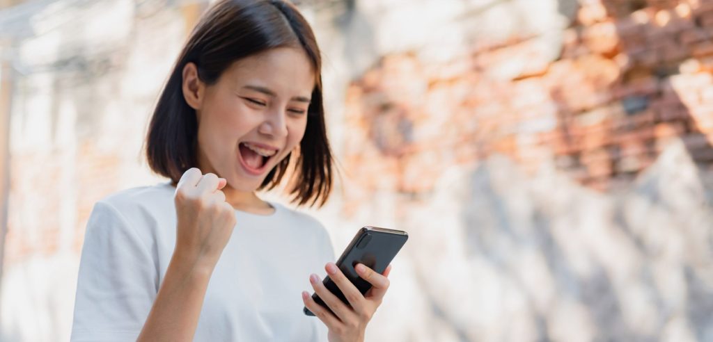 woman cheers after increasing e-commerce conversion rates by optimizing conversion funnel